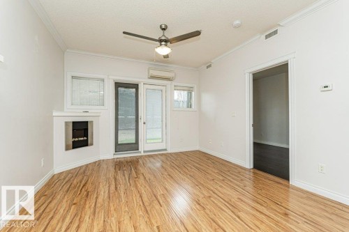 Living area featuring wood-finish flooring, a built-in electric fireplace, and a ceiling fan - 145 10121 80 Avenue, Edmonton, AB - Indoor Photo Showing Other Room With Fireplace