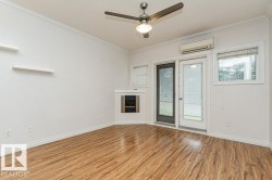 Spacious room featuring wood-finish flooring, a built-in fireplace, a ceiling fan, and multiple windows - 