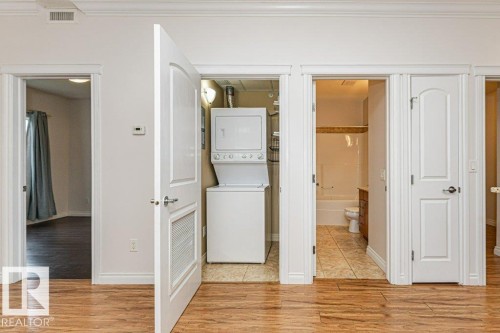 Wood-finish flooring extending through the hallway - 145 10121 80 Avenue, Edmonton, AB - Indoor Photo Showing Laundry Room