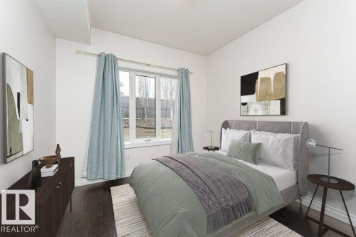 Hardwood-finish flooring features throughout this room with a large window providing ample natural light - 145 10121 80 Avenue, Edmonton, AB - Indoor Photo Showing Bedroom
