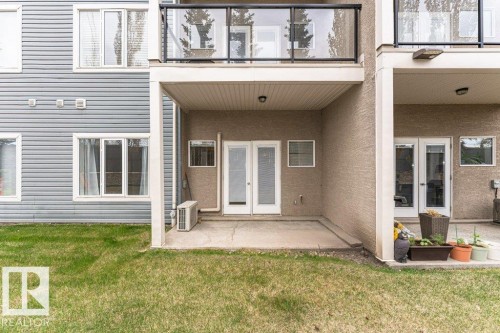 Ground-level concrete patio with covered overhead structure, dual glass panel doors, and exterior wall lighting - 145 10121 80 Avenue, Edmonton, AB - Outdoor With Exterior