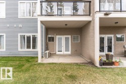 Ground-level concrete patio with covered overhead structure, dual glass panel doors, and exterior wall lighting - 