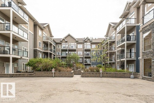Multi-story building exterior featuring balconies with glass railings, stone veneer accents, and gabled rooflines - 145 10121 80 Avenue, Edmonton, AB - Outdoor With Facade