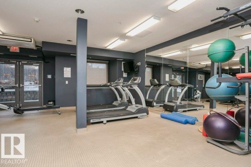 Fitness center with wall-mounted mirrors and neutral-toned carpet flooring - 145 10121 80 Avenue, Edmonton, AB - Indoor Photo Showing Gym Room