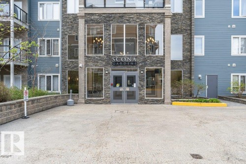 Building entrance featuring stone-clad facade, double glass doors, large window panels, and integrated signage - 145 10121 80 Avenue, Edmonton, AB - Outdoor With Facade