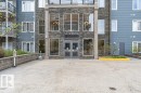 Building entrance featuring stone-clad facade, double glass doors, large window panels, and integrated signage - 145 10121 80 Avenue, Edmonton, AB  - Outdoor With Facade 