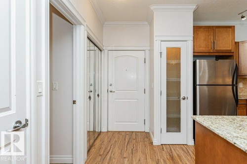 Entryway with wood-finish flooring, crown molding, and a mirrored closet - 145 10121 80 Avenue, Edmonton, AB - Indoor