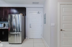 Kitchen area featuring a stainless steel refrigerator, dark wood-finish cabinetry, and light-toned countertop - 