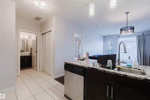 Kitchen island with a granite countertop, stainless steel sink, and gooseneck faucet - 510 5151 Windermere Boulevard, Edmonton, AB - Indoor