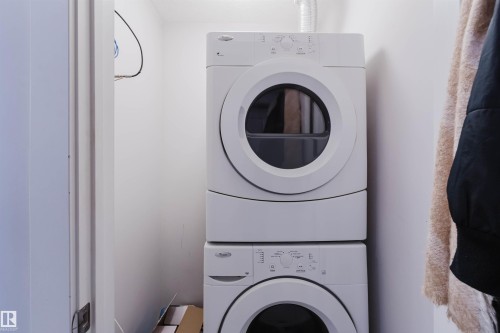 Dedicated laundry area featuring a stacked washer and dryer unit - 510 5151 Windermere Boulevard, Edmonton, AB - Indoor Photo Showing Laundry Room