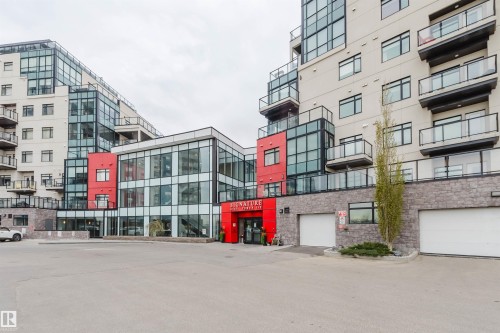 Contemporary multi-story building featuring a prominent red entrance, extensive glass facades, private balconies with glass railings, a stone-clad base, and integrated garage doors - 510 5151 Windermere Boulevard, Edmonton, AB - Outdoor With Balcony