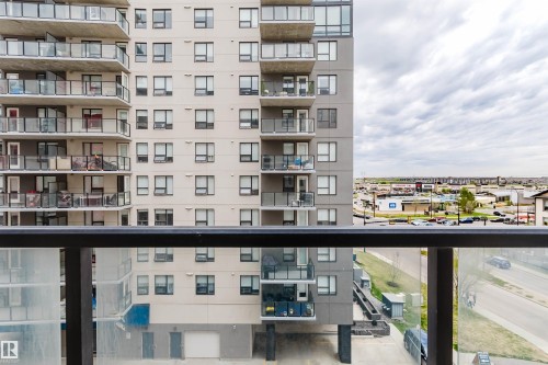 Balcony with clear glass railing and black metal top rail - 510 5151 Windermere Boulevard, Edmonton, AB - Outdoor With Balcony With Facade