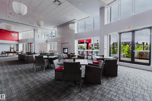 Spacious common area featuring patterned carpet flooring, high ceilings, large windows, recessed lighting, and wall-mounted light fixtures - 510 5151 Windermere Boulevard, Edmonton, AB - Indoor