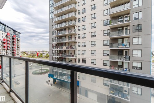 Balcony with glass and metal railing, offering expansive views of surrounding high-rise buildings and development - 510 5151 Windermere Boulevard, Edmonton, AB - Outdoor With Balcony