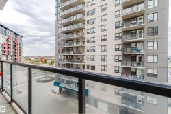 Balcony with glass and metal railing, offering expansive views of surrounding high-rise buildings and development - 