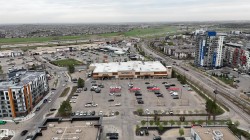 Aerial perspective showcasing an urban landscape with multiple multi-story residential buildings, a commercial center featuring a large grocery store, and extensive parking areas - 