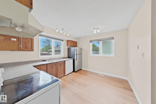 Kitchen featuring wood-finish cabinetry, light countertops, and a double basin sink - 1731 51 Street, Edmonton, AB - Indoor Photo Showing Kitchen With Double Sink