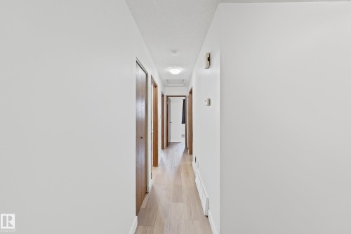 Hallway featuring light wood-finish flooring and multiple brown panel doors - 1731 51 Street, Edmonton, AB - Indoor Photo Showing Other Room