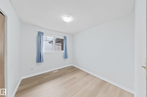 Room with light wood-finish flooring, white walls, and a window featuring light blue curtains - 1731 51 Street, Edmonton, AB - Indoor Photo Showing Other Room