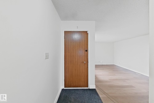 Entrance area featuring a wood-panel door with circular hardware, light-toned wood-finish flooring extending into the interior, and white wall finishes - 1731 51 Street, Edmonton, AB - Indoor Photo Showing Other Room