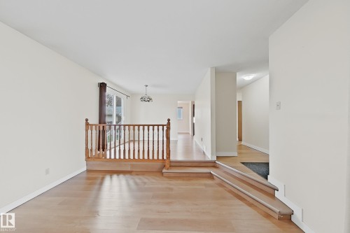 Spacious interior featuring light wood-finish flooring, neutral wall tones, and a wooden banister - 1731 51 Street, Edmonton, AB - Indoor Photo Showing Other Room
