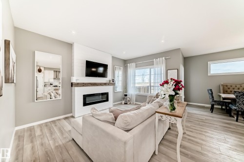 Bright living area featuring wood-finish flooring, a contemporary electric fireplace with a shiplap surround and rustic mantel, and recessed lighting - 38 Prospect Place, Spruce Grove, AB - Indoor Photo Showing Living Room With Fireplace
