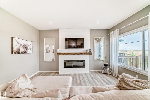 Living area featuring a shiplap fireplace surround with a wood mantel, an electric fireplace insert, and wood-finish flooring - 38 Prospect Place, Spruce Grove, AB - Indoor Photo Showing Living Room With Fireplace
