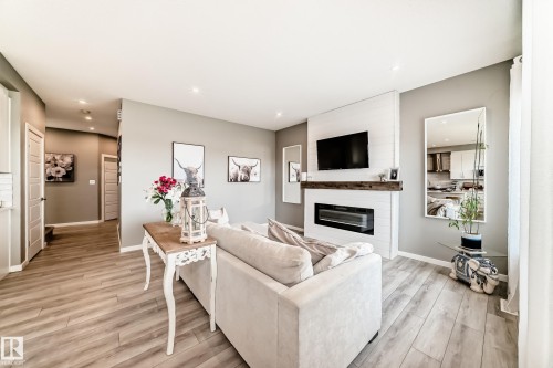 Living room featuring wood-finish flooring, a contemporary fireplace with a white tile surround and rustic wood mantle, recessed lighting, and a neutral color palette - 38 Prospect Place, Spruce Grove, AB - Indoor Photo Showing Living Room With Fireplace