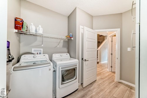 Dedicated laundry area featuring a washer and dryer, elevated wire shelving, and wood-finish flooring - 38 Prospect Place, Spruce Grove, AB - Indoor Photo Showing Laundry Room