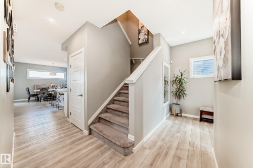 Light wood-finish flooring extending throughout, carpeted staircase with white railing, and flush-mounted ceiling lighting - 38 Prospect Place, Spruce Grove, AB - Indoor Photo Showing Other Room