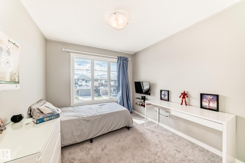 Bright room featuring a large multi-pane window, light gray wall paint, and gray carpet flooring - 38 Prospect Place, Spruce Grove, AB - Indoor Photo Showing Bedroom
