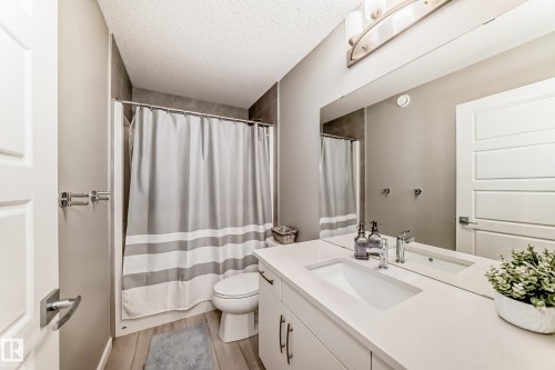 Full bathroom featuring a single vanity with integrated sink, expansive mirror, three-light fixture, and shower with tile surround - 38 Prospect Place, Spruce Grove, AB - Indoor Photo Showing Bathroom