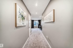 Carpeted hallway featuring light gray walls, white trim, and recessed lighting - 
