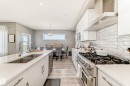 Contemporary kitchen featuring white cabinetry, light-toned wood-finish flooring, and a large central island with a double basin sink - 38 Prospect Place, Spruce Grove, AB  - Indoor Photo Showing Kitchen With Double Sink With Upgraded Kitchen 
