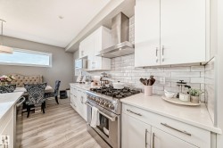 Modern kitchen featuring white cabinetry, light countertops, subway tile backsplash, stainless steel range with hood, and wood-finish flooring - 