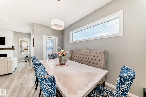 Dining area featuring a horizontal window, wood-finish flooring, and a contemporary drum pendant light fixture - 38 Prospect Place, Spruce Grove, AB - Indoor Photo Showing Dining Room
