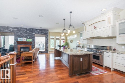 Gourmet kitchen with a large central island, light-toned perimeter cabinetry, stainless steel range, and stone countertops - 2413 Tegler Green, Edmonton, AB - Indoor Photo Showing Kitchen With Fireplace With Upgraded Kitchen