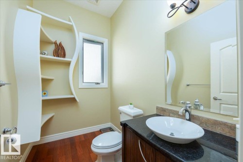 Powder room featuring a vessel sink, dark wood-finish vanity with a dark stone countertop, and a built-in shelving unit - 2413 Tegler Green, Edmonton, AB - Indoor Photo Showing Bathroom