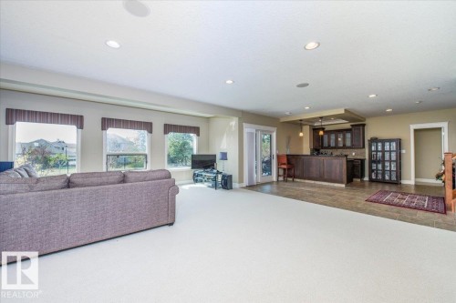 Spacious lower level featuring recessed lighting, a built-in wet bar with dark wood cabinetry and pendant lighting, and light-colored carpeting - 2413 Tegler Green, Edmonton, AB - Indoor Photo Showing Living Room