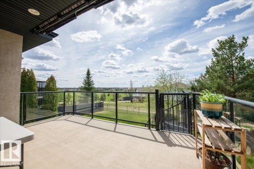 Spacious concrete deck featuring a glass and metal railing system, integrated overhead lighting, and a private gate - 2413 Tegler Green, Edmonton, AB - Outdoor With Exterior