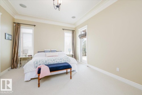 Carpeted room featuring crown molding, neutral wall tones, two large windows with blinds, and a glass-paneled door - 2413 Tegler Green, Edmonton, AB - Indoor Photo Showing Bedroom