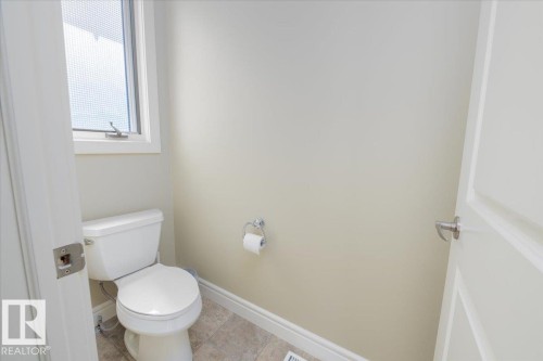 Compact powder room featuring a porcelain toilet and tile flooring - 2413 Tegler Green, Edmonton, AB - Indoor Photo Showing Bathroom