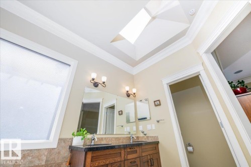 Bathroom featuring a skylight, crown molding, and a double vanity with wood cabinetry - 2413 Tegler Green, Edmonton, AB - Indoor Photo Showing Bathroom