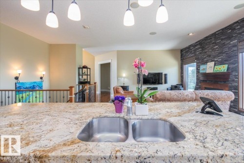 Kitchen island featuring a double basin stainless steel sink set into a speckled countertop - 2413 Tegler Green, Edmonton, AB - Indoor Photo Showing Kitchen With Double Sink