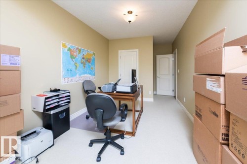 Spacious room featuring neutral-toned walls, cream-colored carpeting, a ceiling-mounted light fixture, and two white paneled doors - 2413 Tegler Green, Edmonton, AB - Indoor Photo Showing Other Room
