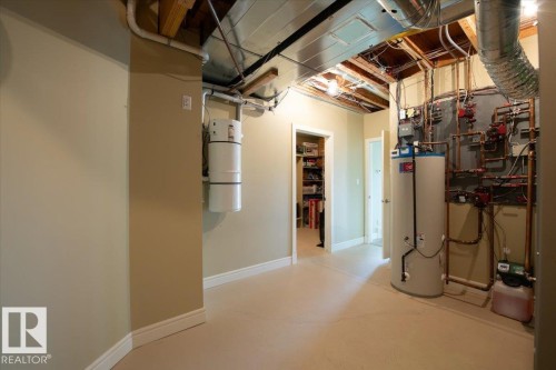 Utility room featuring a central vacuum system, water heater, and exposed mechanical piping - 2413 Tegler Green, Edmonton, AB - Indoor Photo Showing Basement