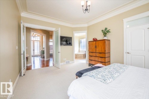 Bright bedroom featuring beige carpeting, crown molding, and a chandelier light fixture - 2413 Tegler Green, Edmonton, AB - Indoor Photo Showing Bedroom