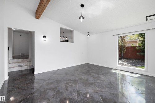 Spacious room featuring large format tile flooring, a prominent exposed wood beam, and a large picture window - 11525 37A Avenue Nw, Edmonton, AB - Indoor Photo Showing Other Room