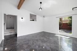 Spacious room featuring large format tile flooring, a prominent exposed wood beam, and a large picture window - 