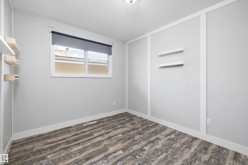 Bright room featuring wood-finish flooring, white baseboards, and a window with a roller shade - 11525 37A Avenue Nw, Edmonton, AB - Indoor Photo Showing Other Room